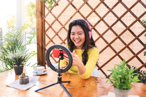 Preview: Asian Influencer Girl Streaming Online With Smartphone Cam Outdoors At Restaurant - Focus On Face