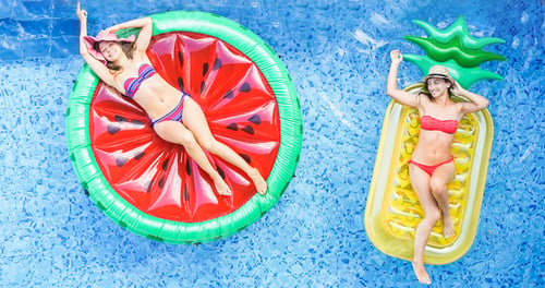 Preview: Happy Girls Floating With Tropical Fruit Lilos Inside Swimming Pool - Young Women Friends Relaxing