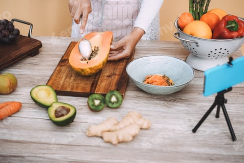 Preview: Young Woman Preparing Fruit Salad While Streaming Online For Webinar Lesson - Focus On Hand Holding