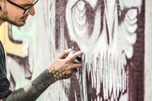 Visualização: Tatuador, grafiteiro, pintando com spray colorido, sua imagem escura na parede - artista contemporâneo