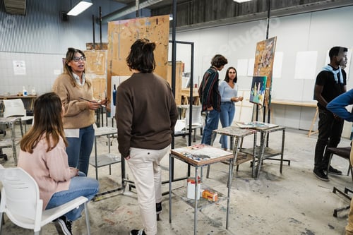 Vista previa: Mature Teacher Working With Art Students During Painting Class At School - Focus On Woman Face