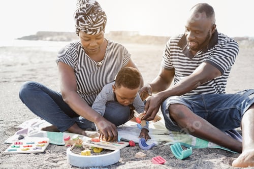 Preview: African Parents And Little Son Having Fun With Wood Toys On The Beach - Main Focus On Man Face