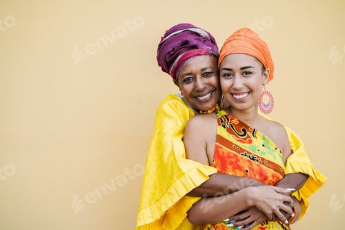 Preview: Happy Mother And Daughter With Traditional African Dresses Smiling On Camera - Focus On Senior