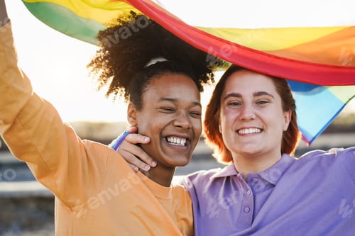 Preview: Happy Women Gay Couple Holding Rainbow Flag Outdoor - Love And Lesbian Concept - Focus On African