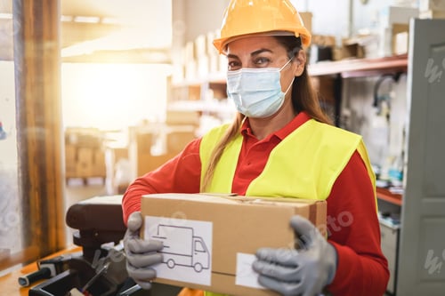 Preview: Hispanic Warehouse Worker Woman Holding Delivery Box While Wearing Safety Mask - Focus On Face