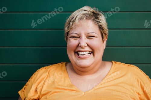 Preview: Portrait Of Curvy Woman Smiling On Camera Outdoors With Green Background - Focus On Eyes