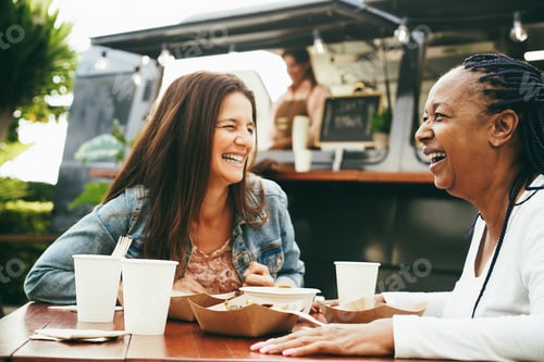 Preview: Happy Multiracial Senior Women Eating At Food Truck Restaurant Outdoor - Focus On African Female
