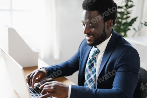 Preview: Business African Man Working Inside Modern Office Using Computer Laptop - Focus On Right Eye