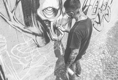 Preview: Tattoo Graffiti Writer Painting With Color Spray His Dark Picture On The Wall - Contemporary Artist