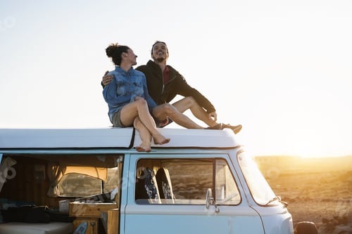 Preview: Happy Couple Sitting On Top Of Minivan Roof At Sunset - Young People Having Fun On Summer Vacation