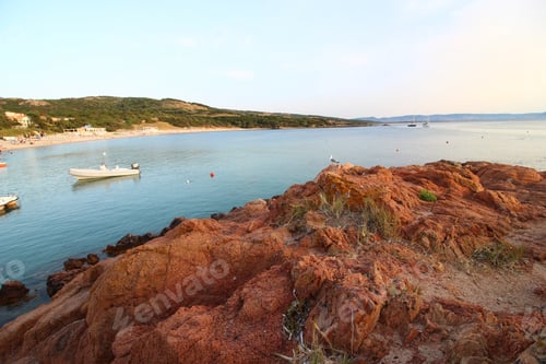 Preview: A Landscape Shot Of A Seashore With A Small White Boat In The Sea, A Green Grass Hill And A Clear