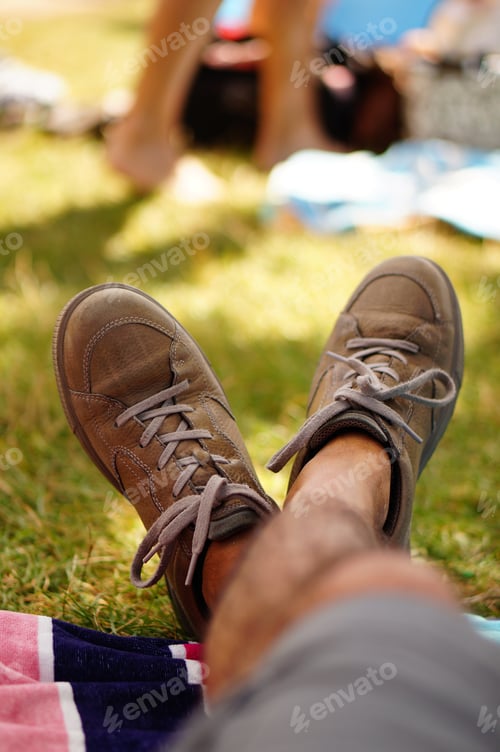 Preview: A Shallow Focus Vertical Shot Of A Person Wearing Brown Shoes In The Park With A Blurred Background