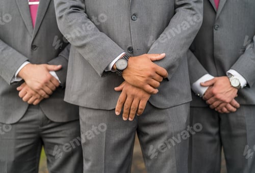 Preview: A Shallow Focus Shot Of Groom And Groomsmen In A Gray Suit With Hands Clasped In Front