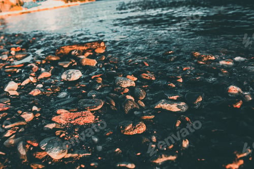 Preview: A High Angle Shot Of The Small Rocks And Pebbles By A Lake Captured At Sunset