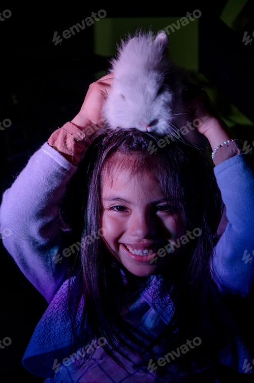 Preview: Happy Little Girl With Her Pet Bunny On Her Head On Dark Background