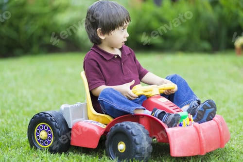 Preview: Happy Little Boy Driving A Toy Car Outdoors