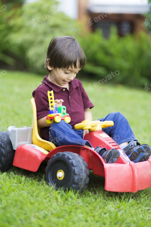Preview: Happy Little Boy Driving A Toy Car Outdoors