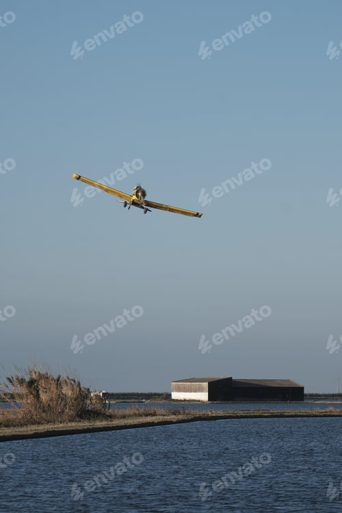 Preview: A Vertical Shot Of A Vintage Single-Engine Aircraft With A Propeller Flying Over A Farm Landscape