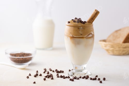Preview: A Soft Focus Of Dalgona Coffee Topped With Chocolate Chips And A Cinnamon Stick