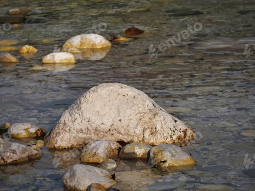 Preview: A Closeup Of A Huge White Rock Inside Of The Water Along With Other Tiny Rocks On The Ground