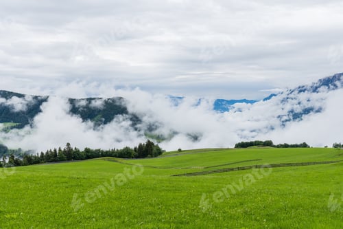 Preview: A Beautiful Landscape Shot Of A Large Field And Mountains Covered By Clouds In South Tyrol, Italy