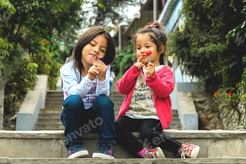 Preview: Two Girls Sitting And Eating A Lollipop In The Park, Summer Outdoor Portrait. Best Friends