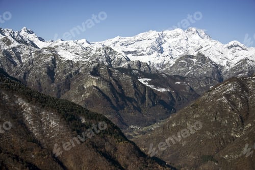 Preview: A Landscape Of Mountains Covered In Trees And Snow Under The Sunlight And A Blue Sky