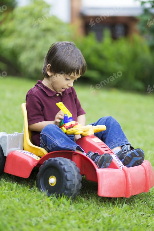 Preview: Happy Little Boy Driving A Toy Car Outdoors