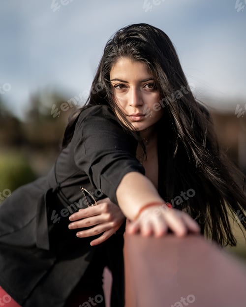 Preview: A Vertical Shot Of A Young Caucasian Woman With Black Long Hair And Heels Leaning On The Fence