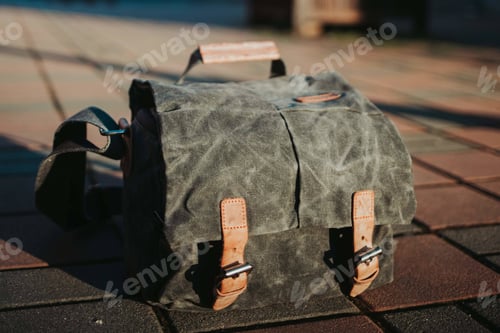 Preview: A Closeup Of A Satchel On The Ground Under The Sunlight With A Blurry Background