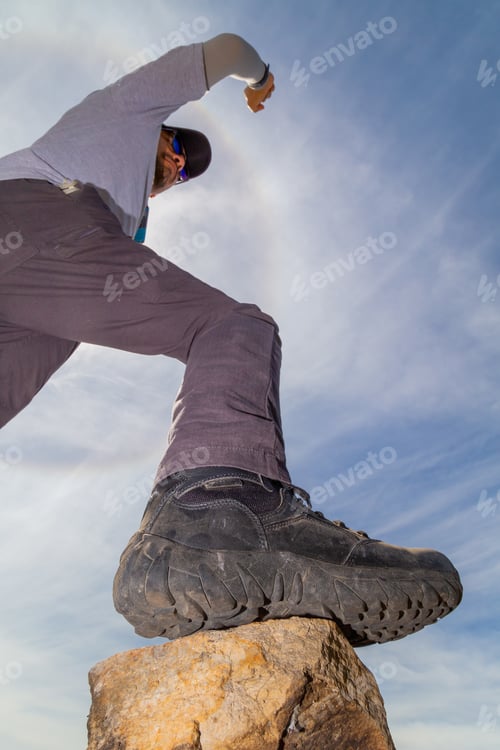 Preview: Low Angle Shot Of A Hiker Putting His Foot On A Rock Climbing A Mountain