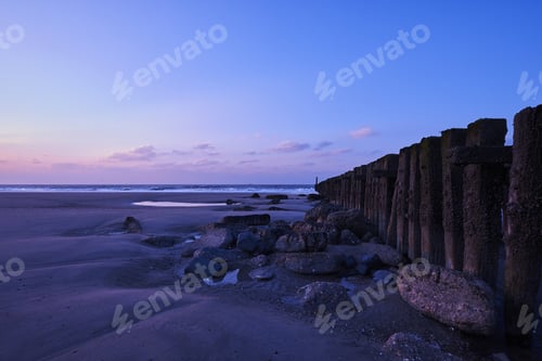 Preview: A Beautiful View Of The Sunset With Purple Clouds Over The Fence On The Beach
