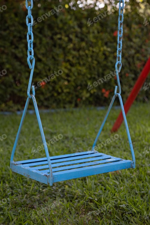 Preview: A Vertical Closeup Of An Old Blue Swing In A Garden Surrounded By Greenery In Mexico
