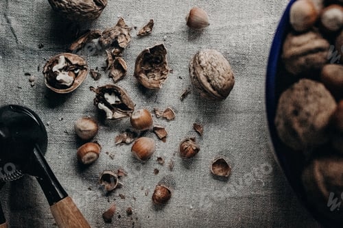 Preview: A Top View Of Broken Walnuts With Hazelnuts And A Crusher On A Fabric Surface