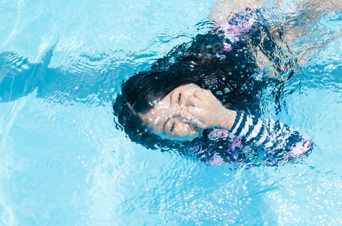 Preview: The Girl In The Pool Swimming Underwater Smiling And Holding Her Nose