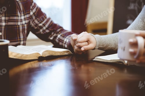 Preview: A Closeup Shot Of A Couple Holding Hands Over The Table White Reading Their Books