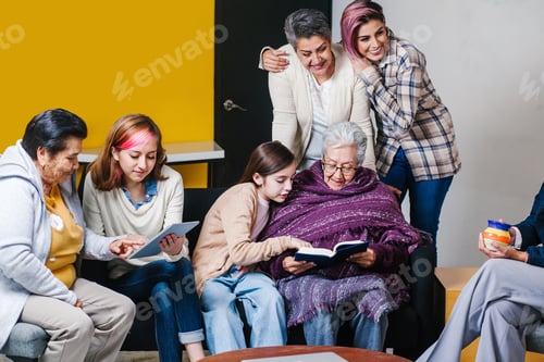 Preview: Latin Granddaughter And Mexican Grandmother Reading A Book And Tablet In Mexico City