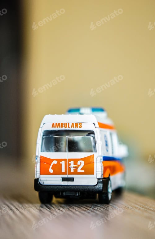 Preview: A Vertical Selective Focus Closeup Of A Toy Ambulance On A Wooden Surface