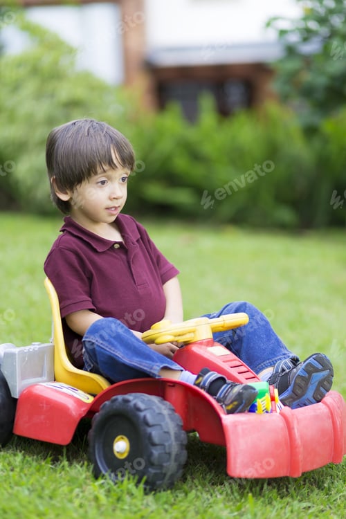 Preview: Happy Little Boy Driving A Toy Car Outdoors