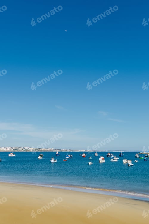 Preview: A Vertical Shot Of Boats On A Sea With A Blue Sky In The Background