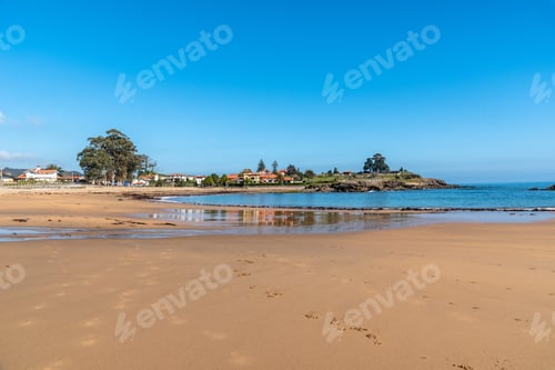 Preview: A Beautiful Shot Of The Coastline With Beach Sand And Buildings On The Shore Under The Blue Sky