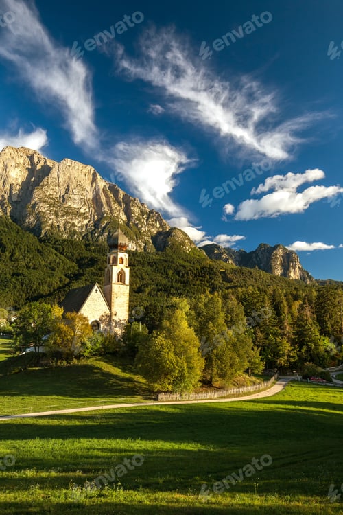 Preview: A Vertical Picture Of A Church Surrounded By Rocks Covered In Greenery Under The Sunlight In Italy