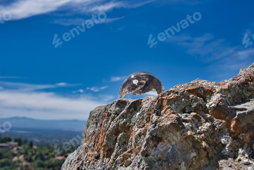 Preview: A Closeup Shot Of A Clear Crystal Ball On Top Of An Outcrop Under The Beautiful Blue Sky
