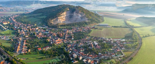 Preview: An Aerial Shot Of A Cityscape Near Beautiful Green Hills With Trees Under The Cloudy Sky