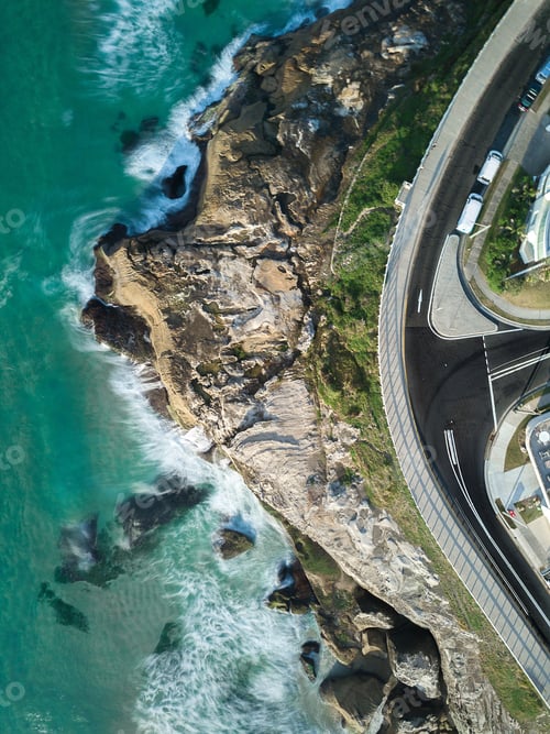 Preview: An Aerial Shot Of A Road Near A Rock Mountain By The Sea