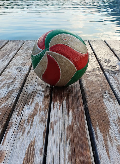 Preview: A Selective Focus Shot Of A Colorful Ball On A Wooden Dock Near The Lake