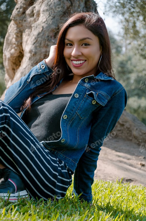 Preview: Portrait Of An Attractive, Young And Attractive Brunette Woman Sitting On The Lawn. She Leans Back