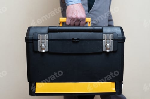 Preview: A Man Wearing A Gray Uniform And Holding A Black Plastic Bag With Instruments