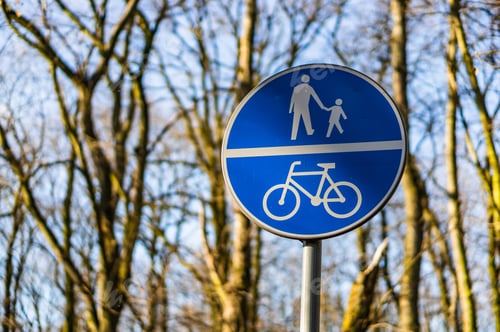 Preview: A Closeup Of A Blue Road Sign For People And Bicycles Under The Sunlight With A Blurry Background