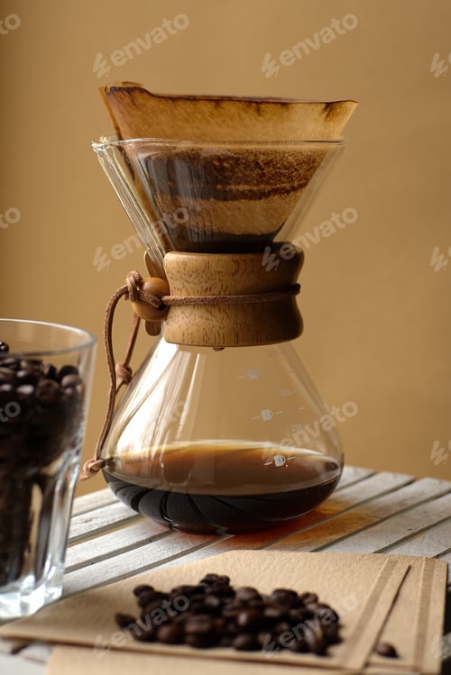 Preview: A Vertical Shot Of A Steaming Coffee Filter And A Glass Cup Filled With Coffee Beans